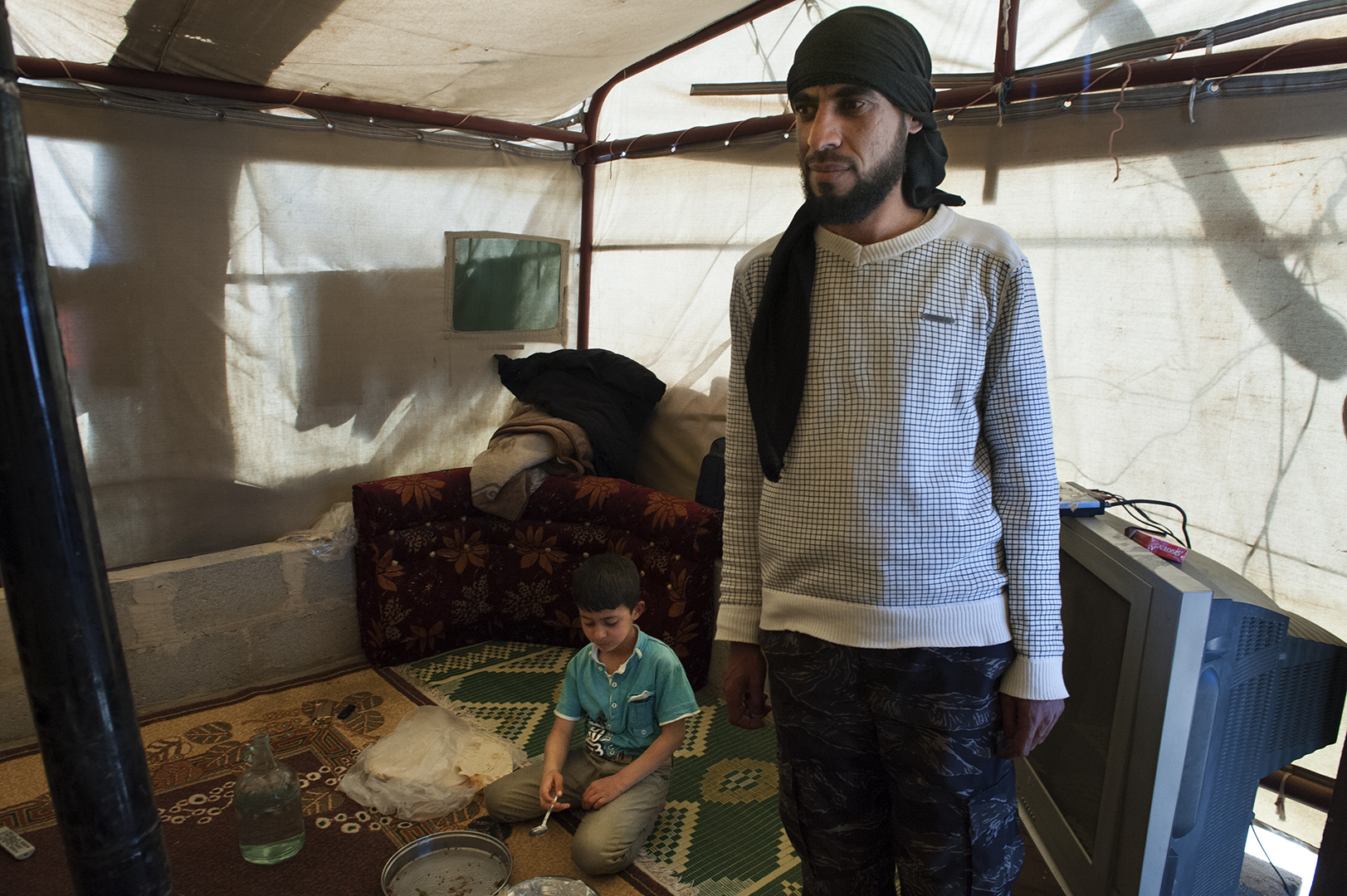 Joven sirio con su hijo en el interior de su tienda en el asentamiento informal de refugiados de Arsal. Líbano 2014